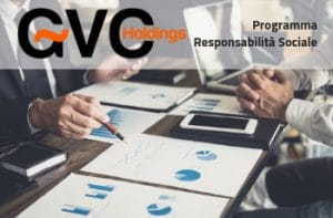 Due uomini a una scrivania esaminano una serie di grafici e dati, tra cartelle di documenti, tablet e computer portatili. Accanto, il logo di GVC Holdings e il titolo Programma responsabilità sociale